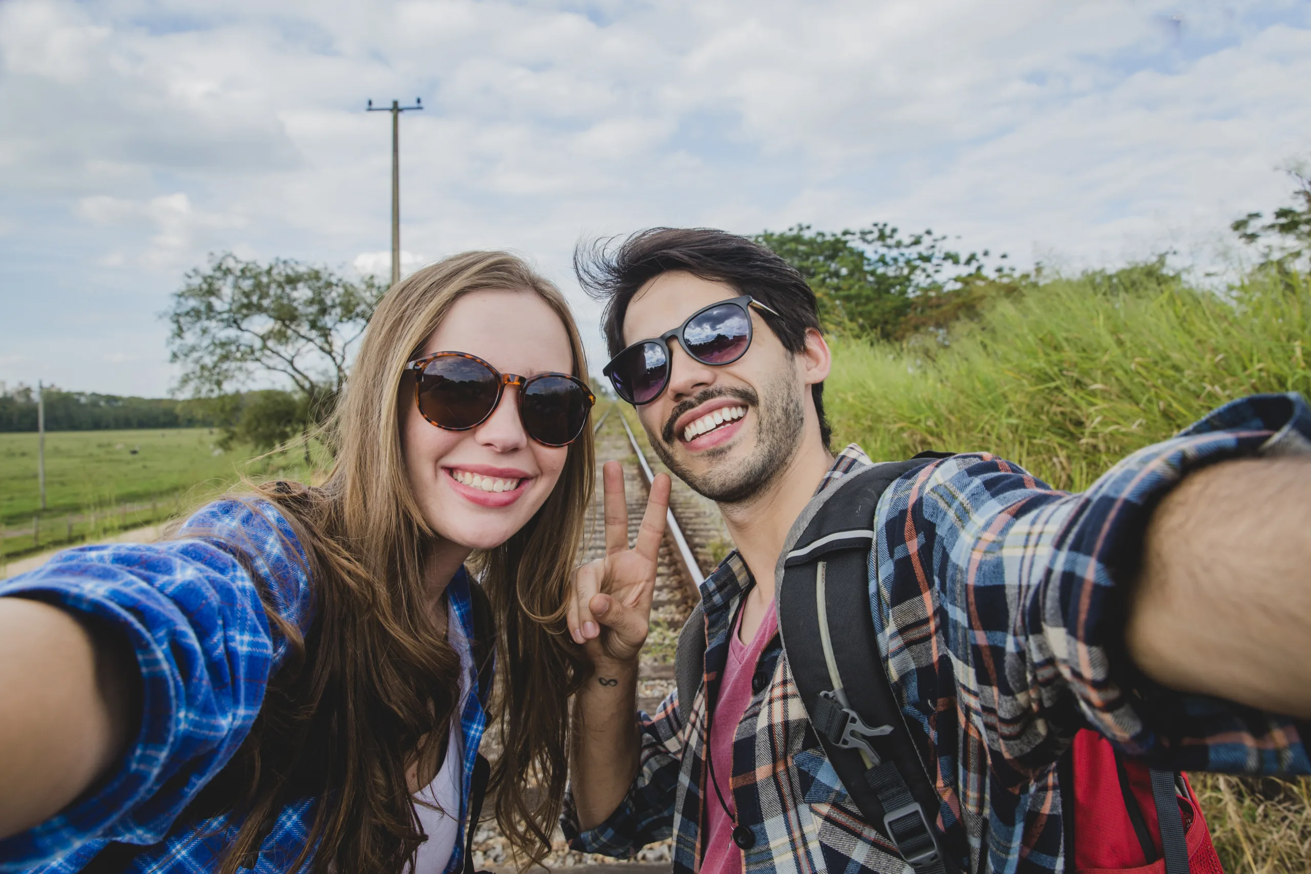 smiling-couple-taking-selfie-train-tracks